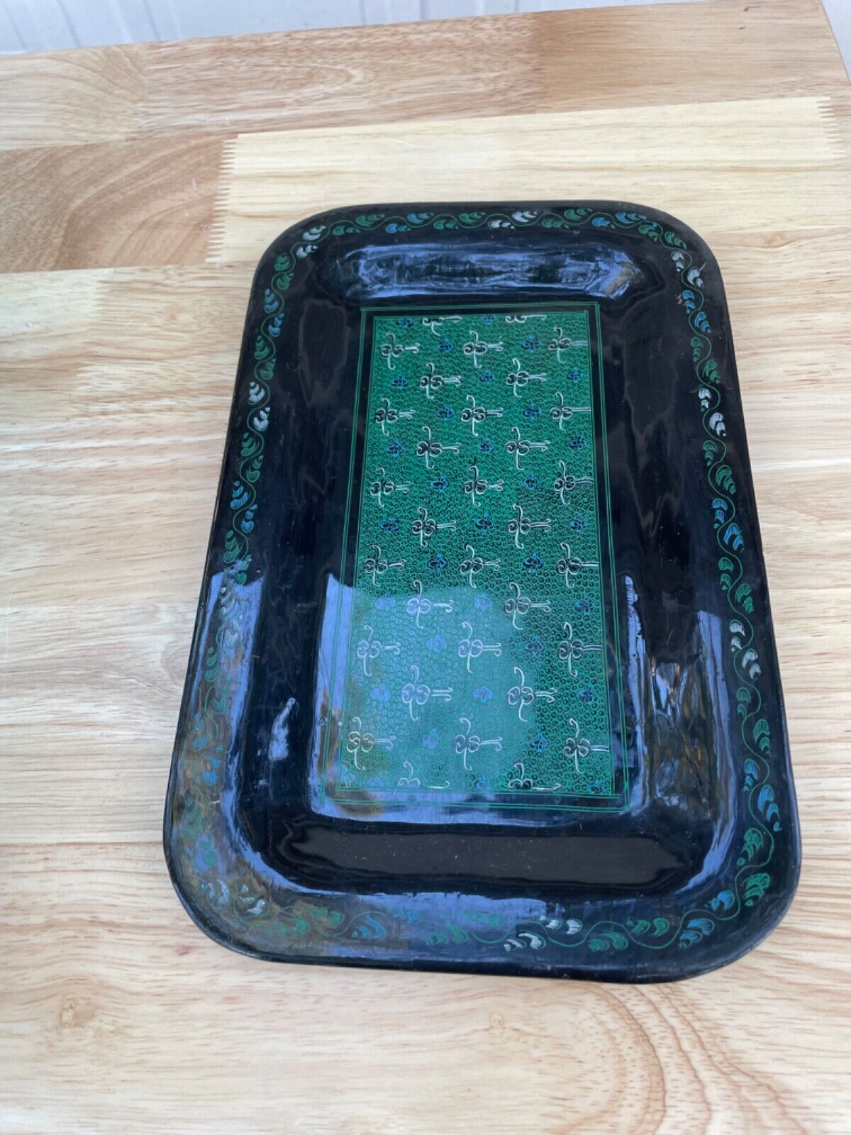 Black vintage valet tray with intricate designs in blue and green