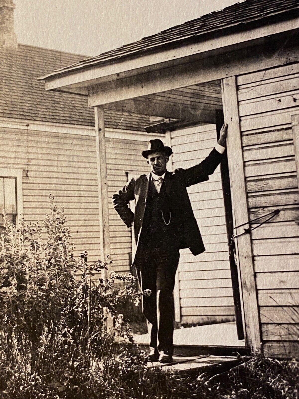1920s RPPC: MAN HOLDING UP A LEANING HOUSE antique real photo postcard AMERICANA