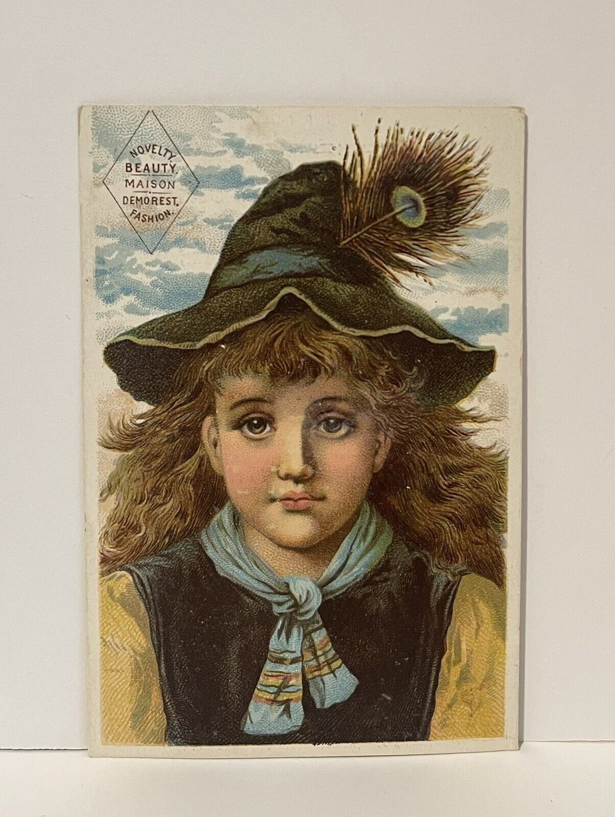 Victorian Trade Card MME DEMOREST’S RELIABLE PATTERN NYC Girl Peacock Feather