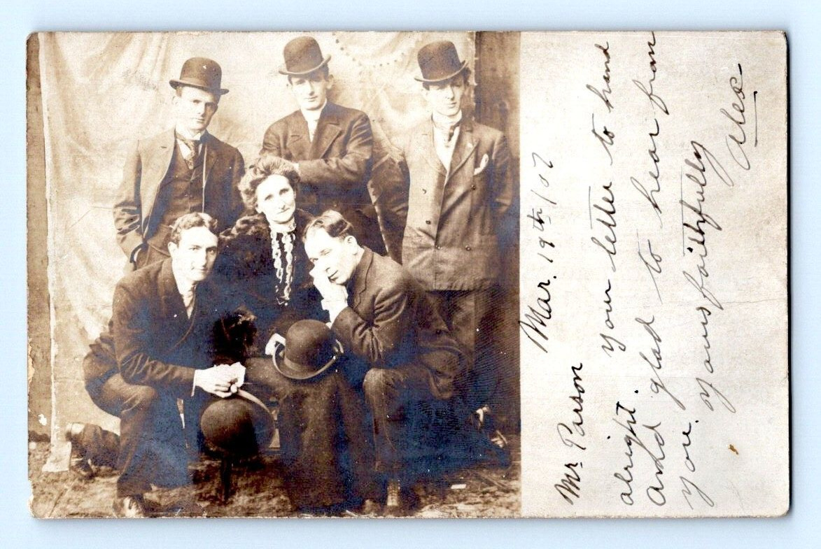 RPPC 1906. MEN SURROUNDING ELDERLY WOMAN. POSTCARD. DD17