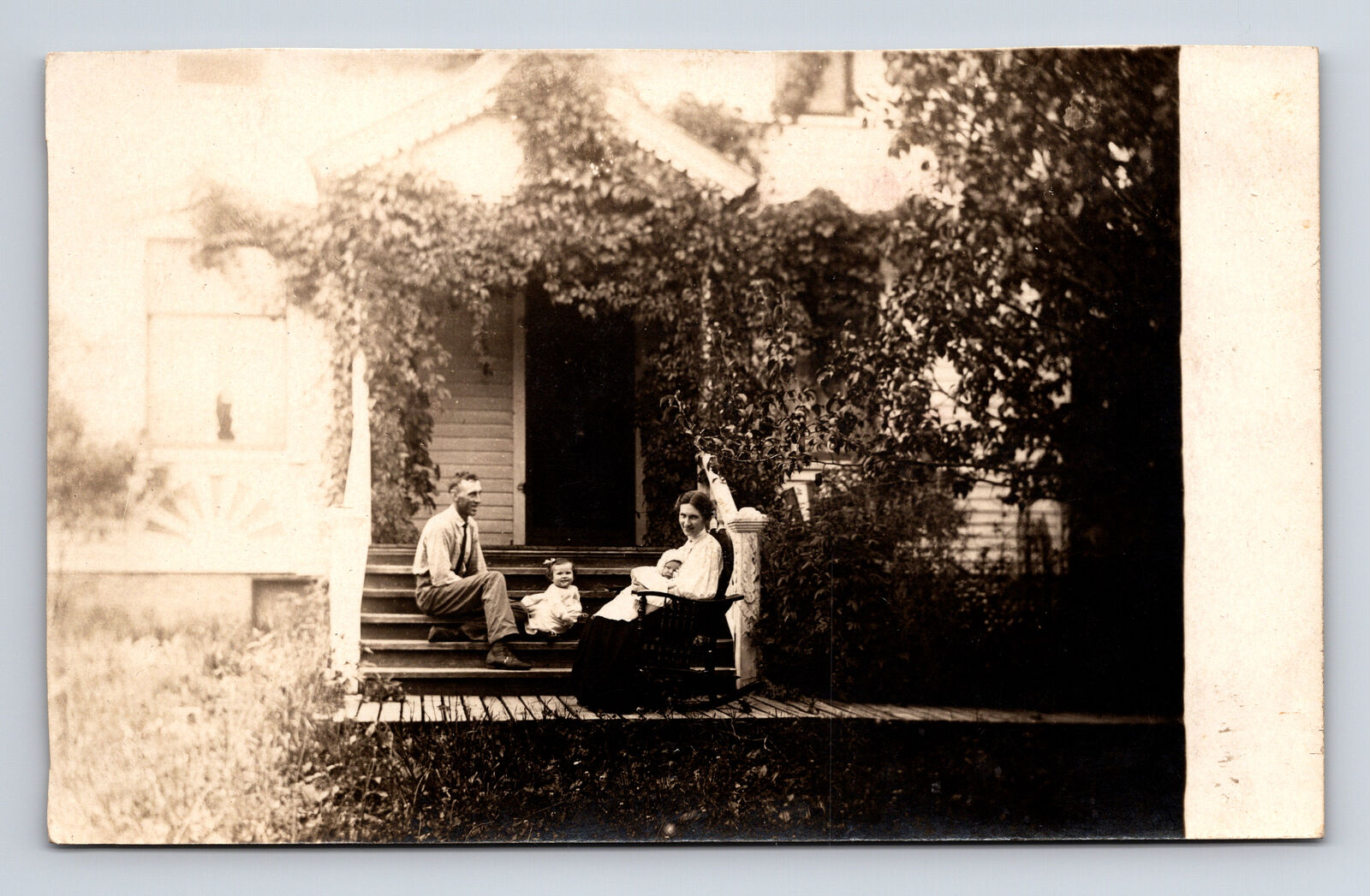RPPC Family Portrait Ivy-Covered Home Rocking Chair Mother Father Baby Postcard