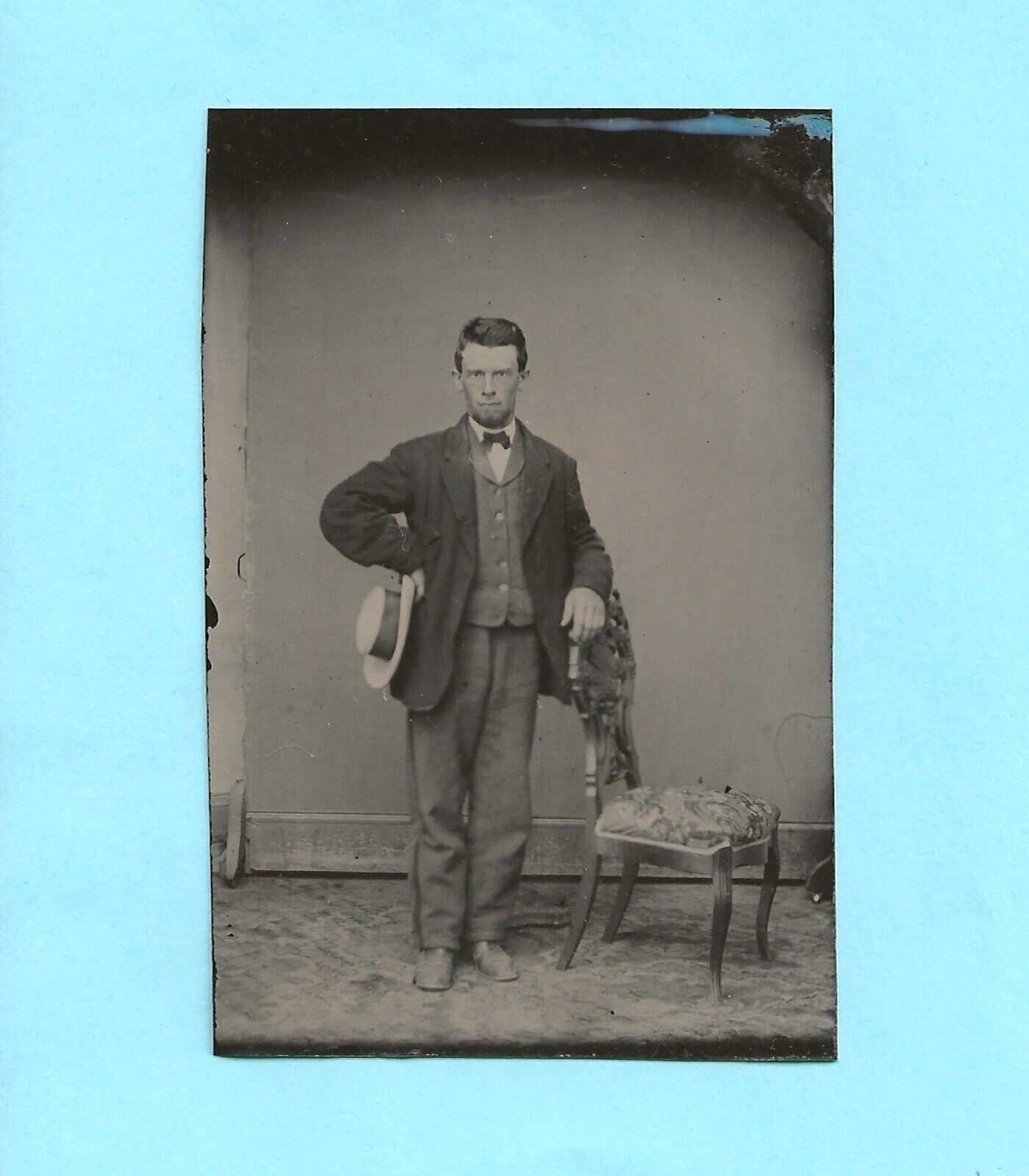 Tintype.  Young man with hand on hip, other on chair.