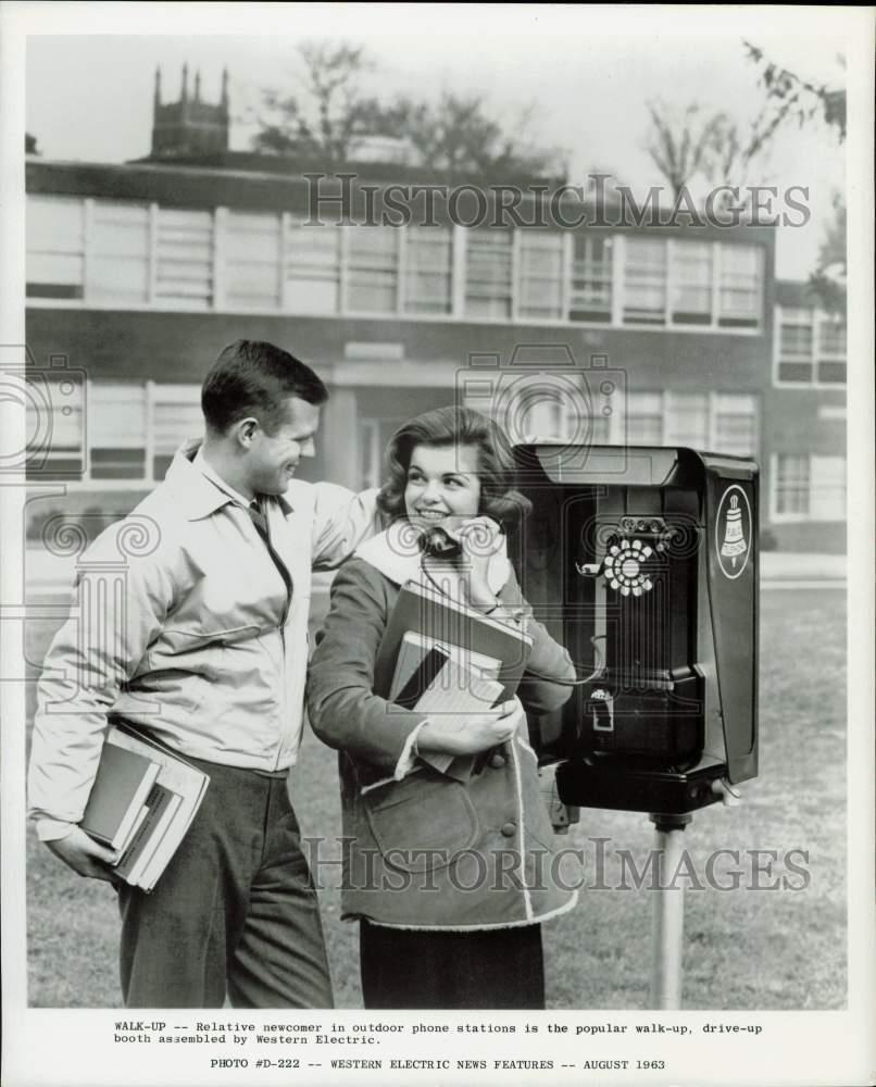 1963 Press Photo Woman using an outdoor telephone station as a man watches