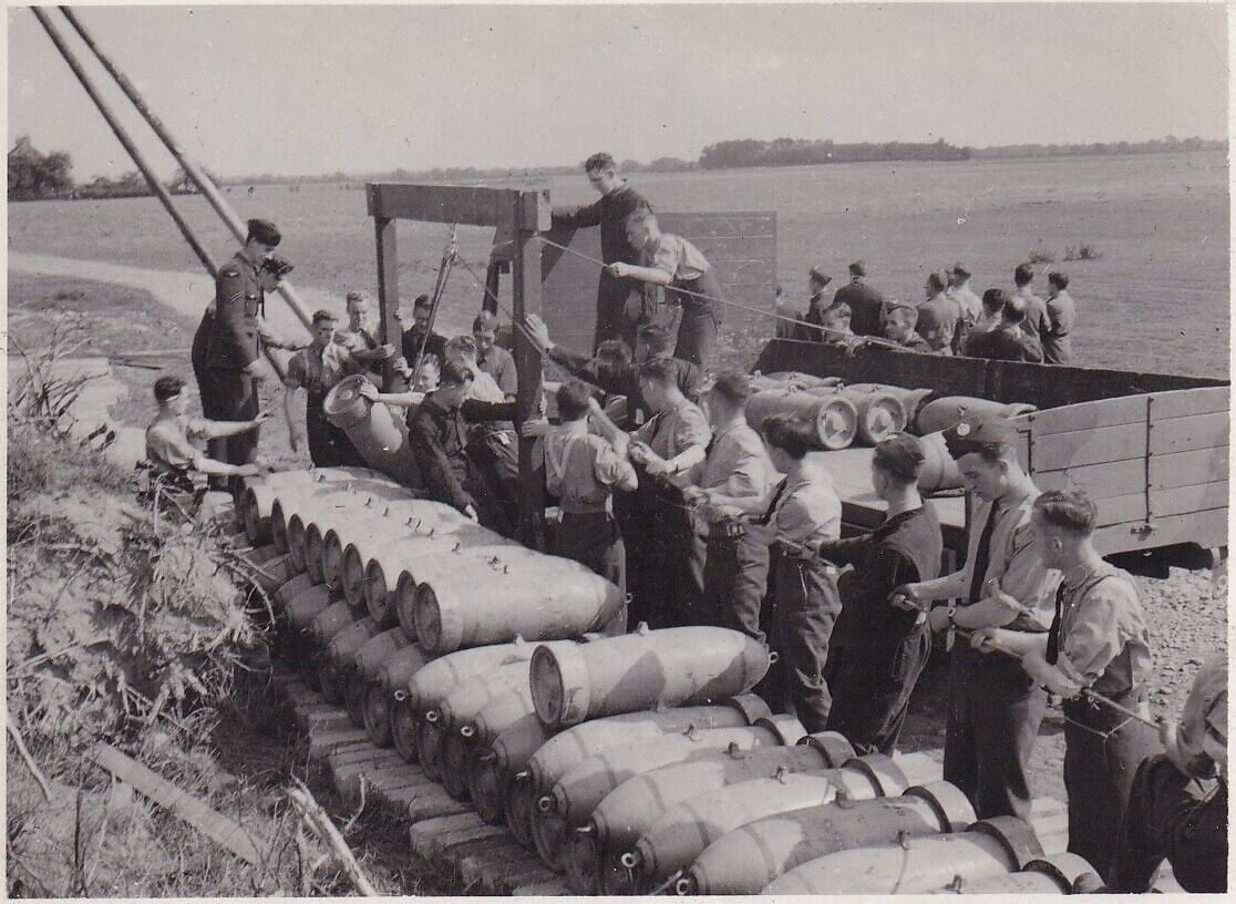 PHOTOGRAPH - ARMOURERS LIFTING A BOMB FROM A LORRY - RAF LINTON ON OUSE - 1943
