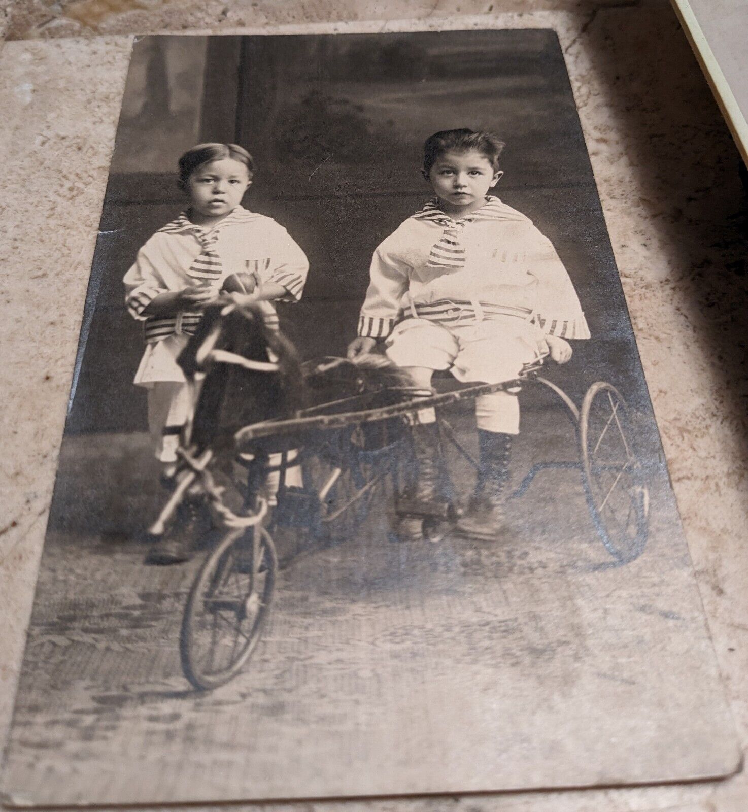 VINATGE RPPC TWO YOUNG CUTE BOYS DRESSED IN SAME CLOTHING, SITTING ON A TRICYCLE