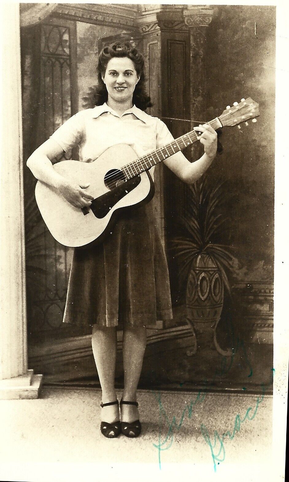 Young woman playing G-chord on old Kay guitar; nice 1910s RPPC