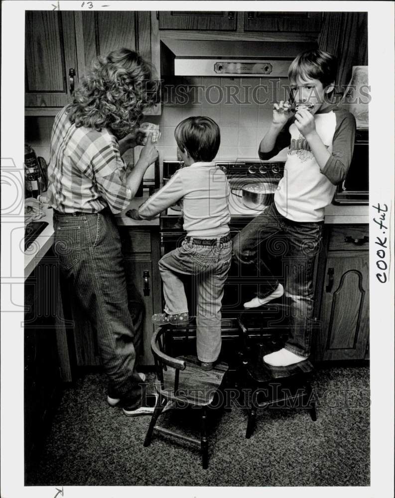 1985 Press Photo Mother and children cook dinner together - lra78642
