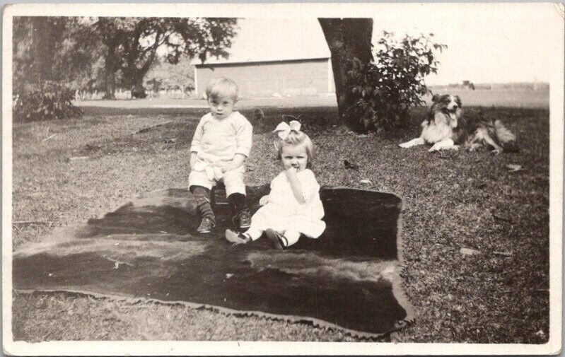 c1920s Real Photo RPPC Postcard Boy & Girl on Blanket in Yard / Dog Nearby