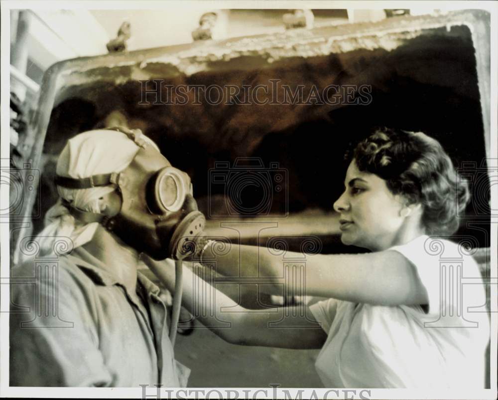 1962 Press Photo Raga adjusts worker\'s gas mask at textile plant in Cairo