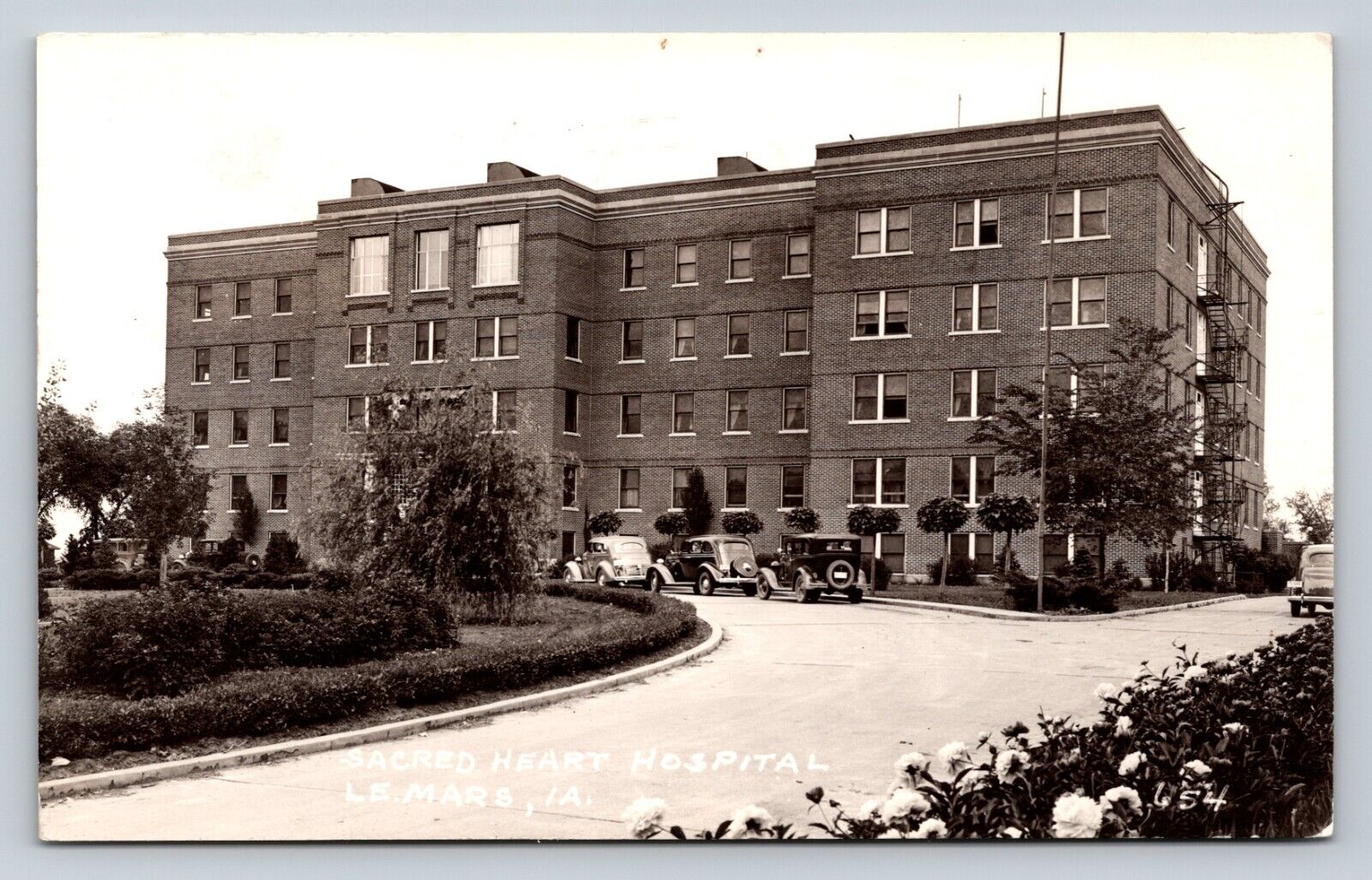 c1948 RPPC Sacred Heart Hospital LE MARS Iowa, Classic Cars VINTAGE Postcard 1c