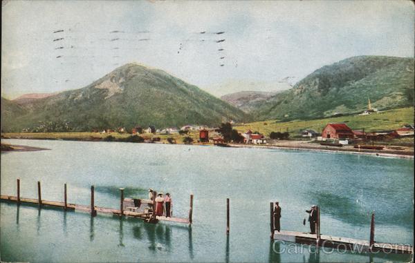1911 Palmer Lake dock with people fishing and town in view across the lake,CO