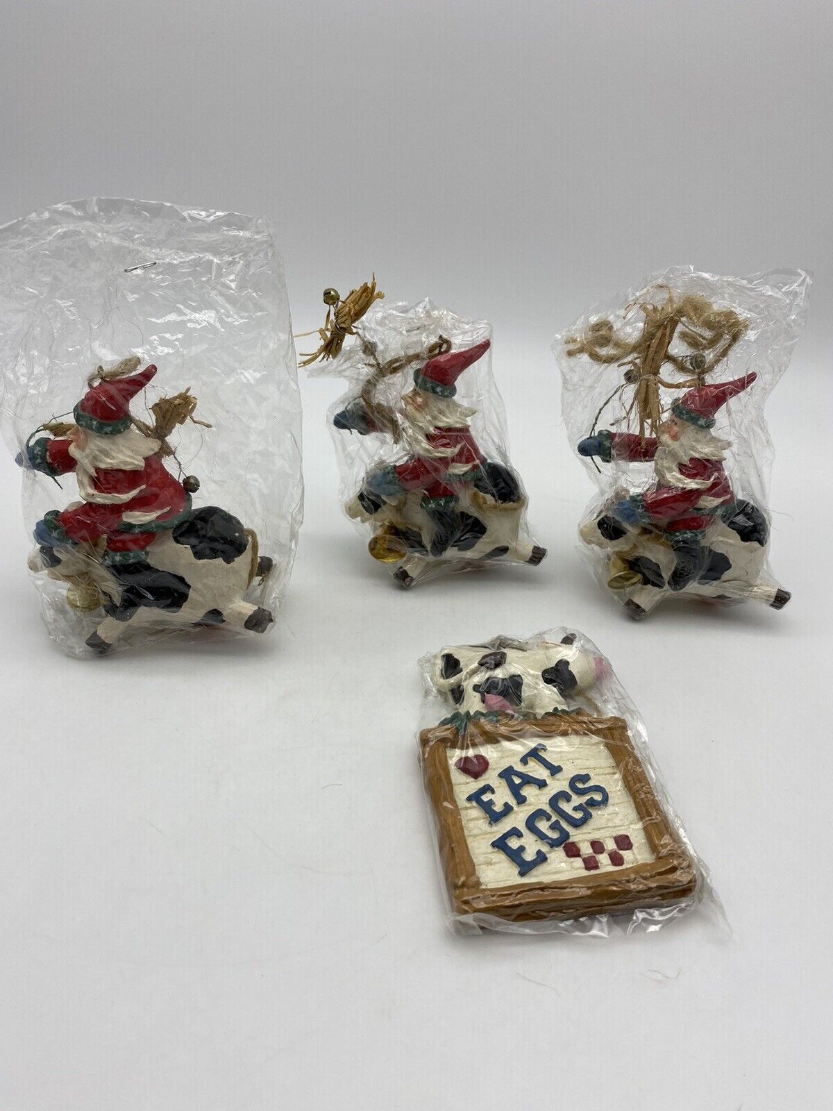 3 Santa Claus Riding Black and White Cow with Bell Ornament & Eat Eggs Ornament