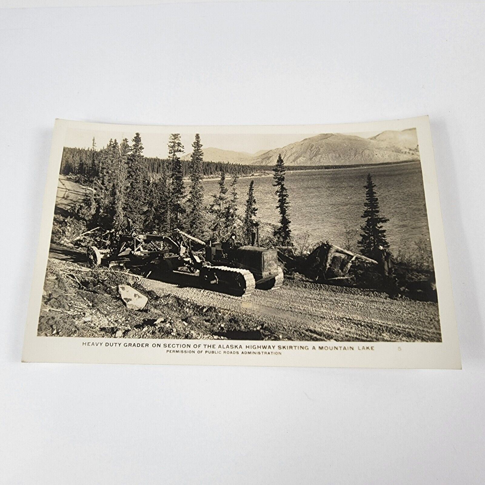 Postcard Heavy Duty Grader On Alaskan Highway Skirting Mountain Lake RPPC