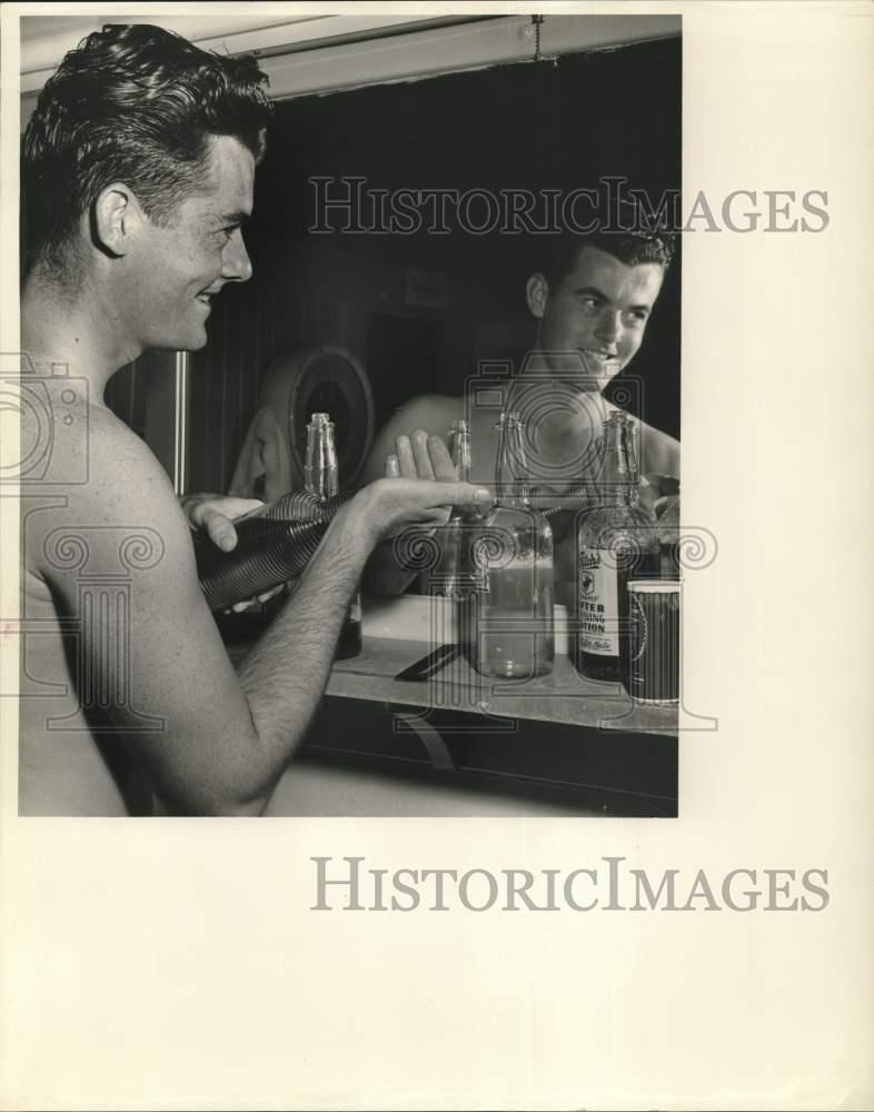 1959 Press Photo Sportsman Tom Burke, Jr. splashes on after-shave lotion.