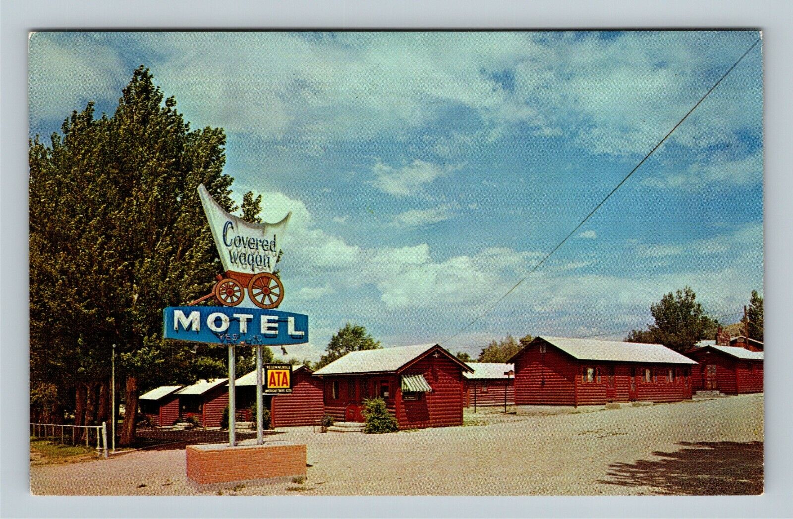 West Cody WY, Covered Wagon Motel Log Cabins Street View Chrome Wyoming Postcard
