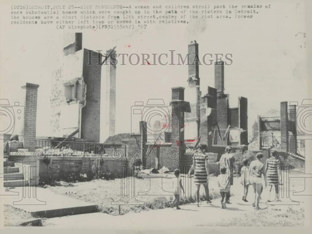 1967 Press Photo A family walks past riot-burned homes in Detroit, MI
