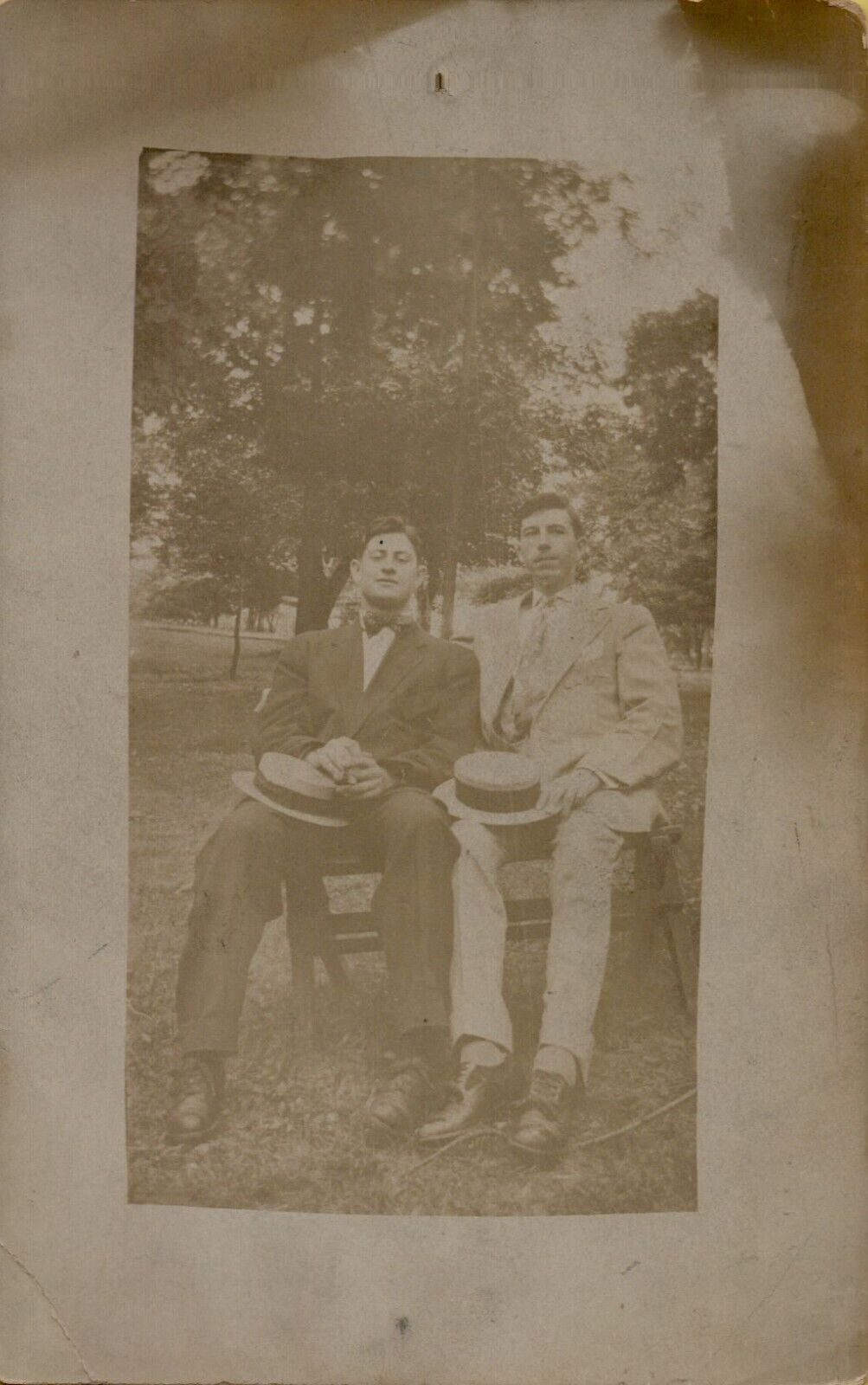 c1910s RPPC of Two Men in Suits with Hats in Laps Outside Real Photo Postcard