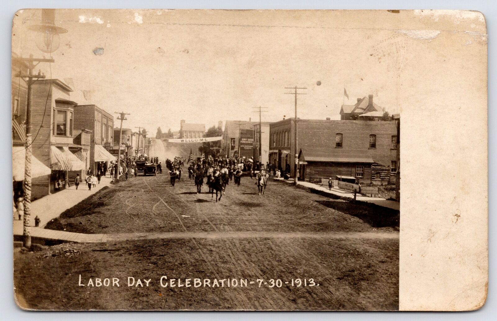 L'anse MI Labor Day Parade on Main St~Welcome Banner~Lumber Yard? Log Cabin~RPPC