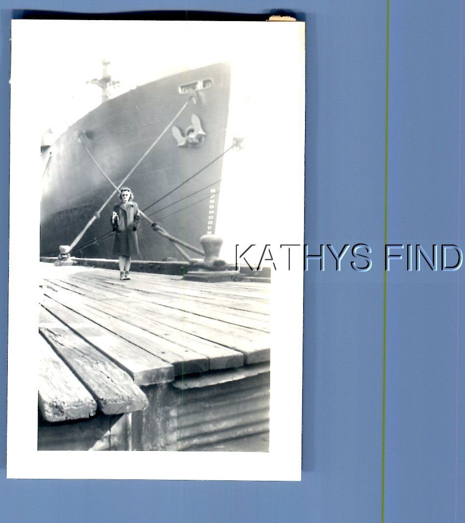 FOUND B&W PHOTO E+6561 PRETTY WOMAN IN COAT POSED ON DOCK BY MILITARY SHIP