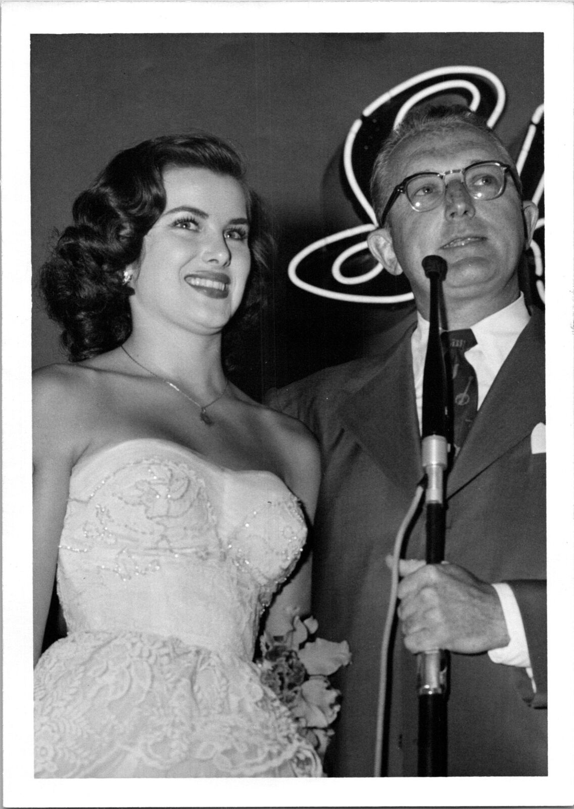Pretty woman in wedding dress next to man w/microphone Found Photo V0509