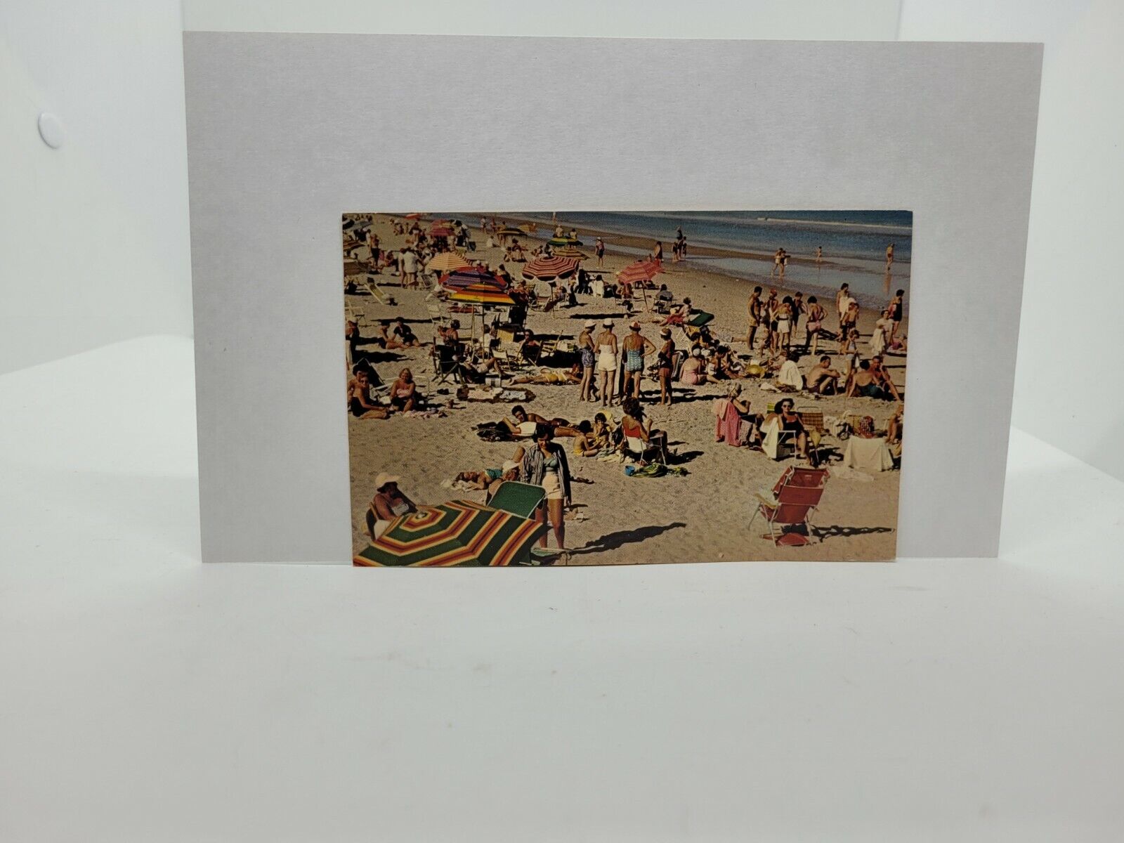Postcard Beach full of people ocean umbrellas sun bathing sand