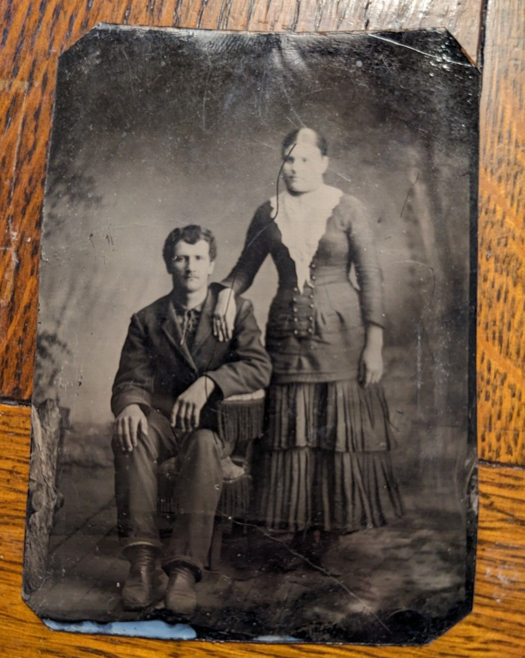 Later 1800's tintype photograph young couple woman & seated man painted backdrop