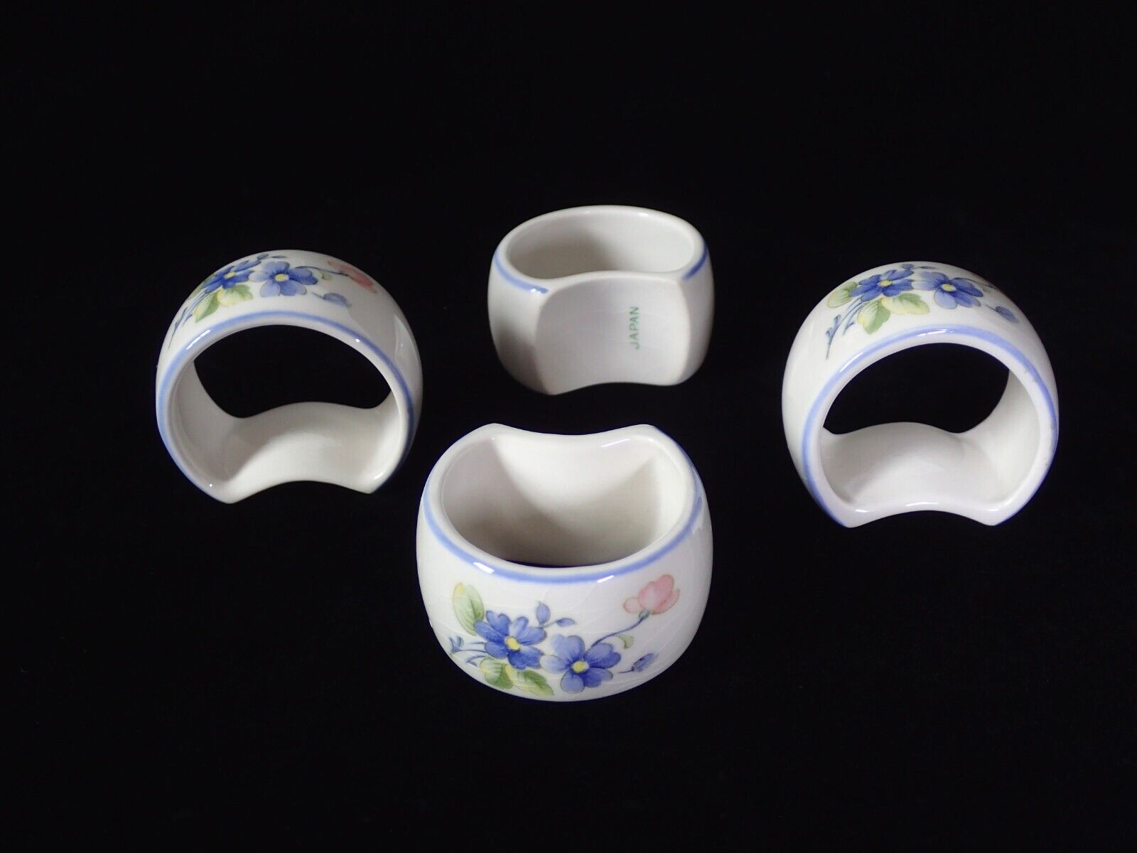 Nikko Tableware Napkin rings/Holders, Set of 4. Floral pattern with blue edges.