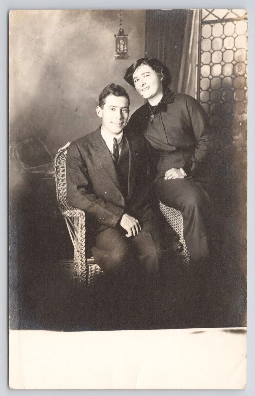 RPPC Smiling Couple Sitting On Chair In Studio c1910 Real Photo Postcard