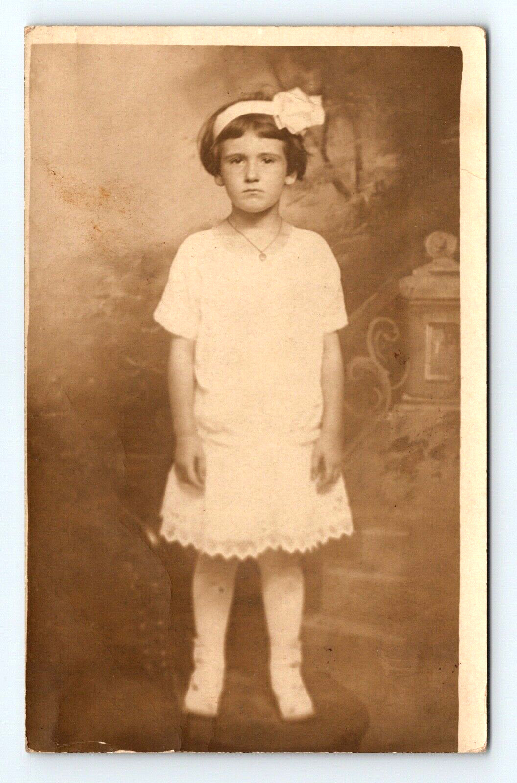 RPPC Young Girl White Dress Hair Bow Stockings Boots Frowning Studio Posed  Z172