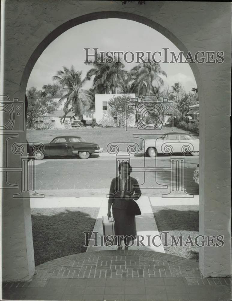 1957 Press Photo Woman Approaching Archway of Home in Miami with Suitcase