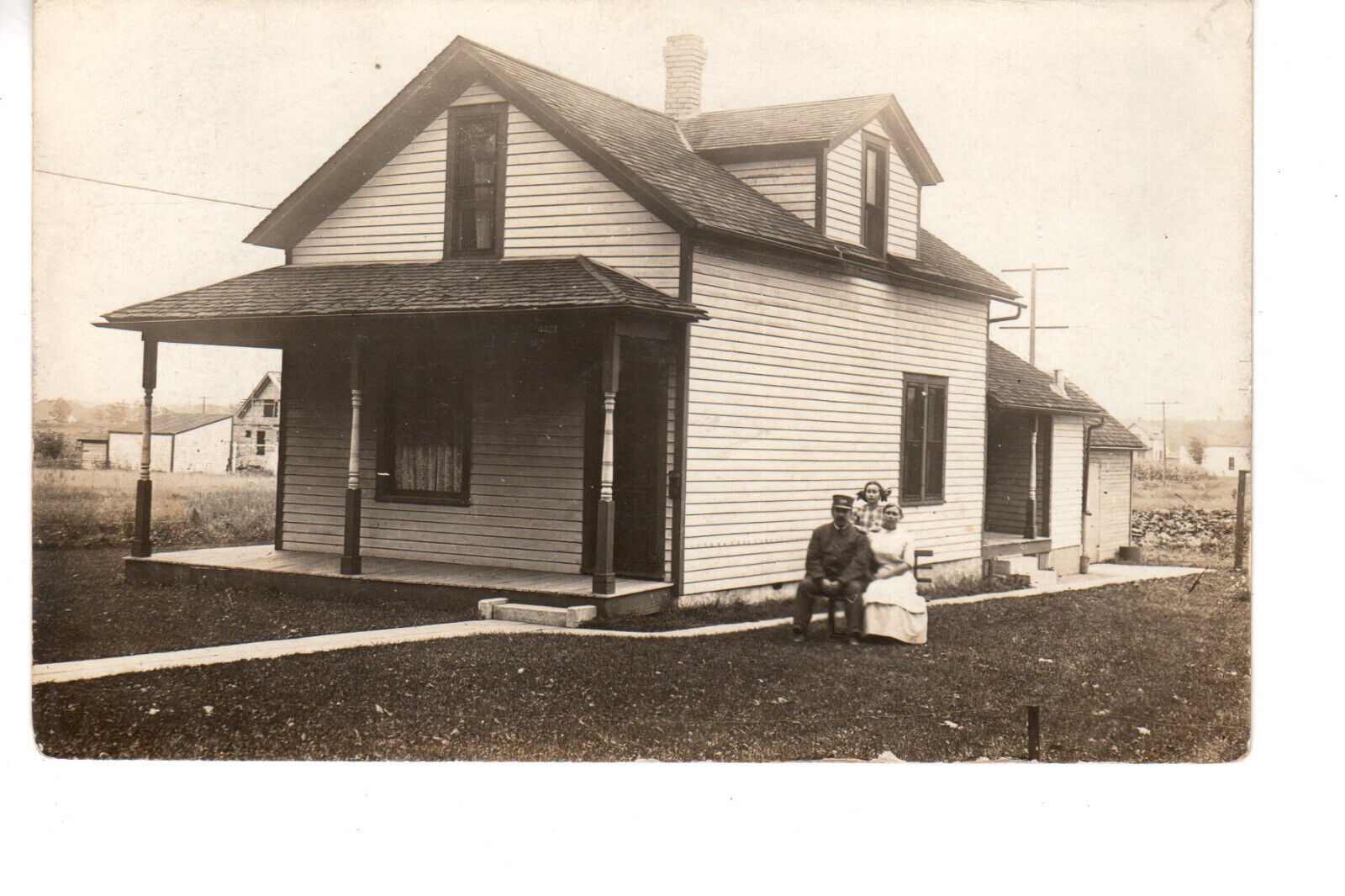RPPC Postcard: Clapboard house; family - man wearing conductor RR-style hat