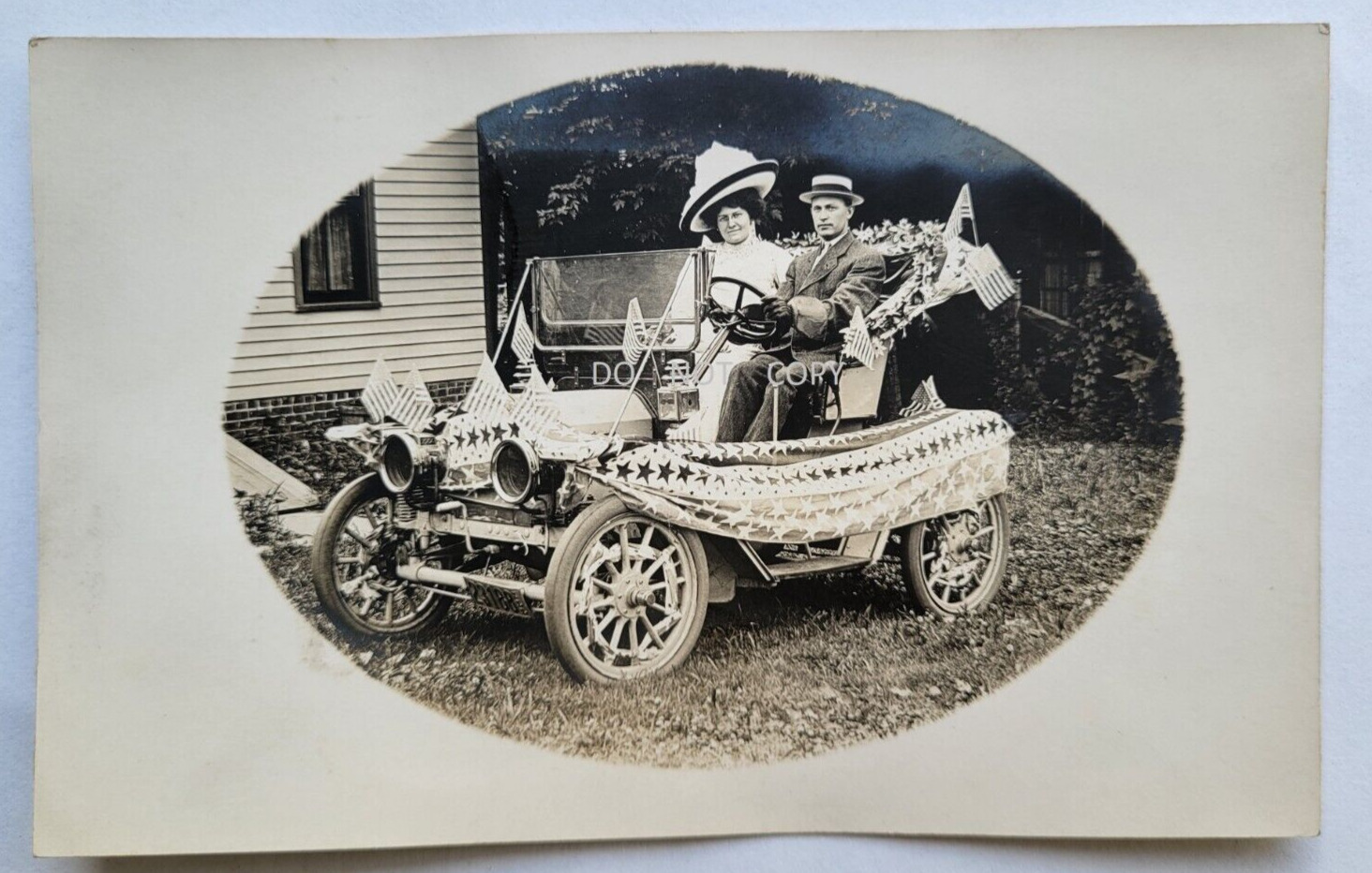 1910\'S RPPC POSTCARD...COUPLE IN CAR DECORATED WITH MANY AMERICAN FLAGS ILLINOIS