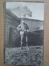 postcard of man holding shotgun by log building 1911 picture