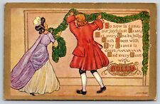 Holiday~Couple Hanging Up Wreath Holly Greeting~Vintage Postcard picture
