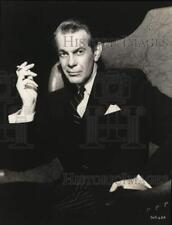 1950 Press Photo Actor Raymond Massey Sits in Chair, Smokes Cigarette picture