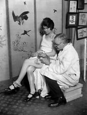 Woman having an image a snake tattooed onto her thigh by tattooist- 1930s Photo picture