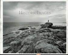 1965 Press Photo Man standing on a rock overlooking the ocean at Pemaquid Point picture