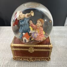 Musical Christmas snowglobe. Boy plays trumpet girl holds doll. 
