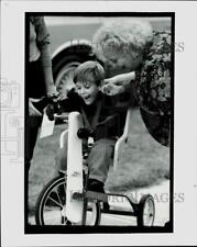 1990 Press Photo Justin Barnes is helped by Marilyn Steehn onto custom tricycle picture