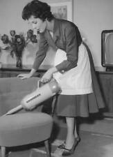 Housewife vacuums an armchair with a handheld vacuum cleaner from - Old Photo picture