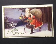 A Joyous Christmas Santa in the Snow w/ Lantern Gold Embossed Postcard c1920s (b picture