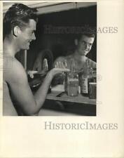 1959 Press Photo Sportsman Tom Burke, Jr. splashes on after-shave lotion. picture
