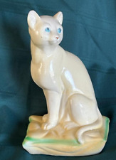 Vintage white ceramic cat with bright eyes, sitting on a pillow picture