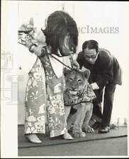 1969 Press Photo Model and stage manager urge a lion during fashion show picture
