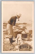 1940s RPPC MAN COOKING LOBSTER ON BEACH smoking pipe wearing hat picture