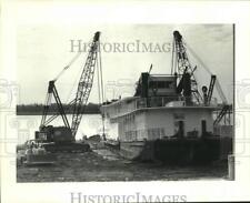 1983 Press Photo Robert E. Lee (Paddlewheel) lifted by cranes on shoreline picture