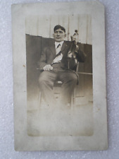 VINTAGE RPPC~REAL PHOTO POSTCARD~MAN IS SITTING ON A CHAIR AND HOLDING A VIOLIN picture