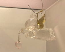 Clear acrylic angel w/ gold metal wings holding light pink heart. 3.5