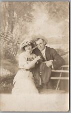 Postcard RPPC 1900s Young Woman Big Hat Man Couple Sitting on Bench Portrait   picture